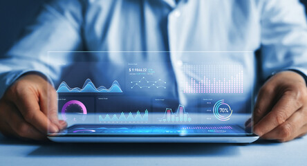 Businessman holding tablet with growing virtual hologram of statistics, graph and chart.Chart graph elements for data analytics and statistics. Stock market investment.