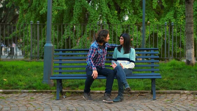 Lovers kissing on park bench and are surprised by his girlfriend that divides them
