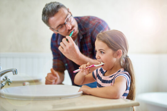 She knows how important brushing her teeth is. Shot of a father and his daughter brushing their teeth.