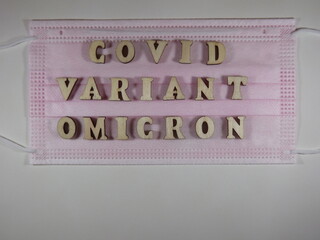 The word covid variant omicron in wooden letters on the face mask. High quality photo