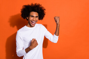 Photo of sweet lucky guy wear white shirt arm rising arms empty space isolated orange color background