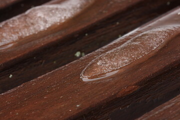 Melting snow on a brown wooden bench