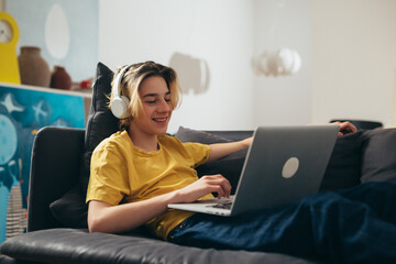 teenager using laptop computer and using headphones