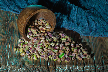 Scattered pistachios from a bowl on a wooden background. Close-up.