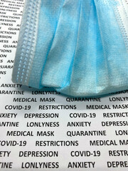 Medical mask on a paper with text containing COVID-19, quarantine, loneliness, depression,...
