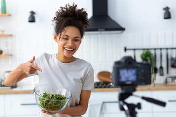 Healthy diet eating. Smiling African American woman food blogger cooking healthy food, breakfast or dinner on camera in home kitchen. Healthy lifestyle concept