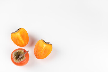Persimmon fruits lie on a white background. Top view, copy space, horizontal orientation.
