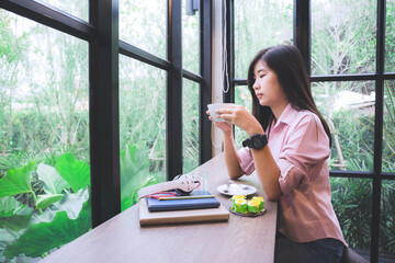 Asian girl in a coffee shop,Lifestyle, Technology Concept - Asian woman using app on a smart phone while relaxing in cafe during free time with copy space.