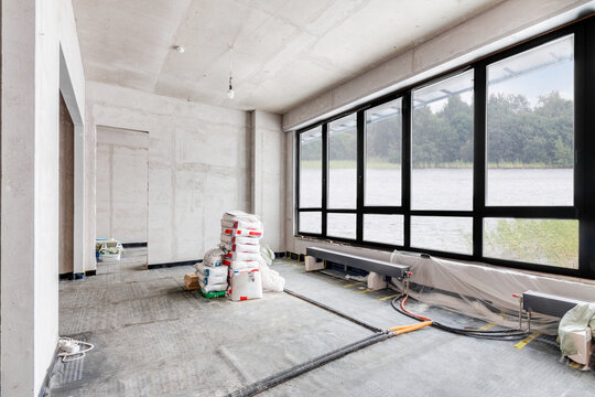 Reconstruction house. Building construction interior site with concrete walls and green nature sustainability background view from the large window.