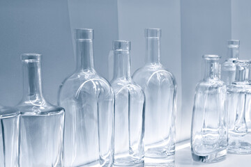 Empty glass bottles in a row on a shelf in blue tone, isolated on white background