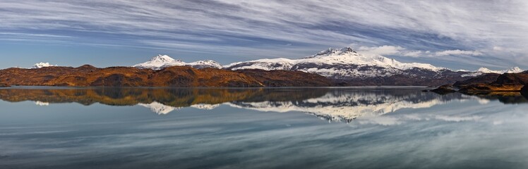 Fototapeta na wymiar Ultra wide panorama of a landscape with snow covered mountains reflecting in a lake (Lago Pehoe) in Patagonia, Chile