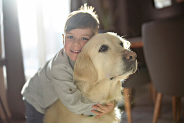 Kid play with puppy. Little boy and golden retriever at home