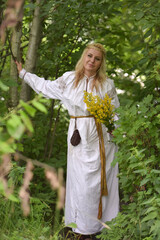 woman in a white slavic shirt among the greenery in summer