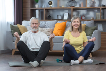 senior man and woman in the house doing yoga, family on a mat, in the lotus position looking at the camera together, morning exercise and fitness