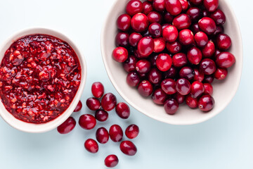 Cranberries in white bowl on pastel background.