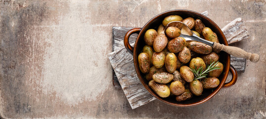 Pan filled with roasted potatoes shot on rustic wooden table.