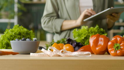 Young Woman Makes a Diet Plan of Correct Nutrition Using a Tablet in the Kitchen