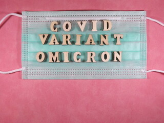 The word covid variant omicron in wooden letters on the face mask. High quality photo