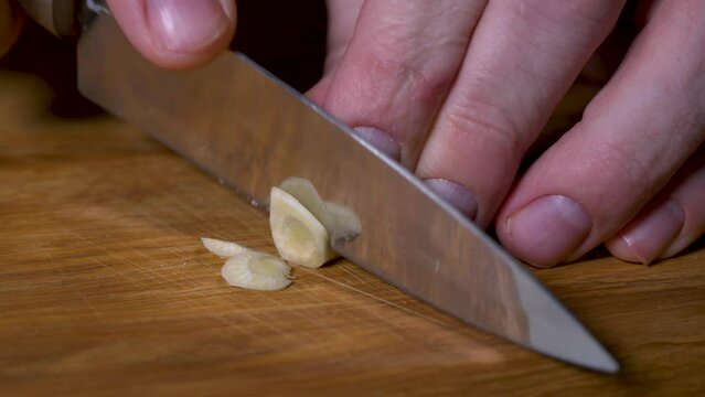 chef grinds garlic on a wooden cutting board, close-up, selective focus 