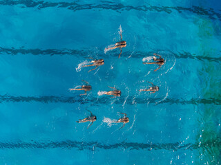 Aerial view of group synchronized swimmers performance with legs