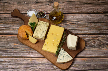Variety of international cheese specialties on a wooden cutting board. Large cheese assortment 
