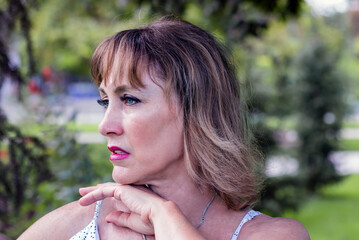 portrait of a beautiful middle-aged woman, 50-55 years old, in profile, against the backdrop of green nature
