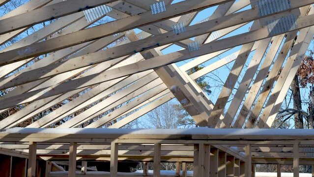 Wooden roof truss being installed on a new home construction project with blue sky in the background. Hand held clip.