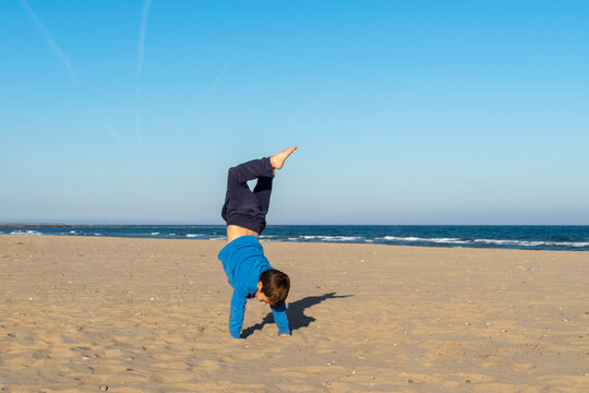 ni&ntilde;o peque&ntilde;o haciendo parkour  en una playa de arena paradisiaca , en un bonito d&iacute;a con el cielo azul .