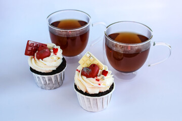 chocolate cupcakes with cream cheese icing and festive decor and tea in glass cups. Valentine's day or birthday dessert. A beautiful festive treat for a wedding or children's party.