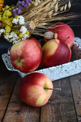 ripe red apples lie on a wooden surface against a dark brick wall. apples on a rustic background.