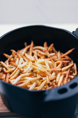 Air fryer with french fries on the worktop