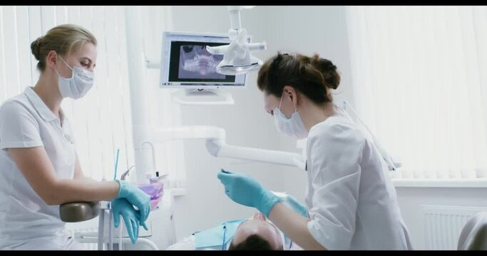 A woman dentist takes instruments and examines the patient's oral cavity