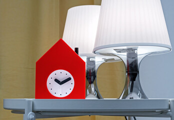 Alarm clock in the form of a red house on a coffee table with lamps.