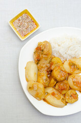 Chicken leg or thigh,potato, ripe plantain and green, vegetable sauce (tomato, onion, garlic) and spices. Typical Colombian food. Chicken stew. White plate. Sudado de pollo. White background. Chili.