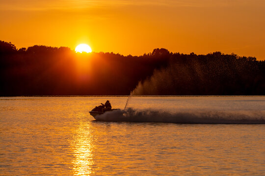 A woman riding a wave runner through the sunset at Shenango River Lake near Hermitage, PA