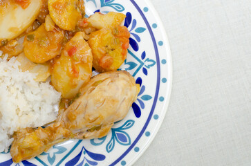 Chicken leg or thigh,potato, ripe plantain and green, with vegetable sauce (tomato, onion, garlic), rice and spices. Colombian food. Chicken stew. Colorful plate. Sudado de pollo. White background.