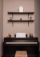 Piano with headphones and blurred sheet music and candle holders against the wall with shelf, vase,...
