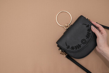 Black leather bag isolated on beige background. Fashion handbag. Composition of clothes. Flat lay,...