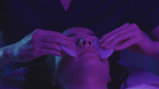 Woman massagist doing a face massage using jade pieces