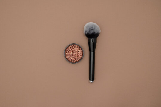 Powder brush and mixed colored glow face pearls blush on bright background. Top view with copy space.