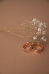 Wedding ring and dried baby’s breath flowers on beige background.