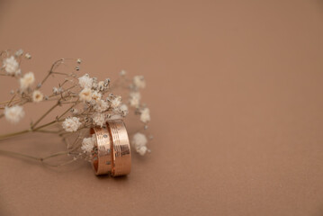 Wedding ring and dried baby’s breath flowers on beige background.