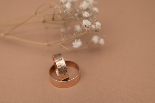 Wedding ring and dried baby&rsquo;s breath flowers on beige background.