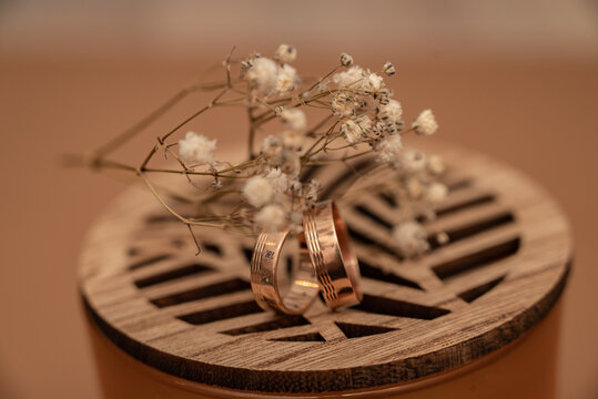 Wedding ring and dried baby&rsquo;s breath flowers on beige background.