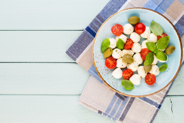 Delicious caprese salad with ripe cherry tomatoes and mini mozzarella cheese balls with fresh basil leaves.