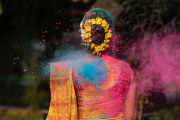 Holi festival of color,Splash of dry organic color or colour or gulal or abeer or Holi powder on a beautiful young girl woman lady in indian attire saree playing celebrating enjoying holi