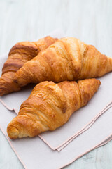 Tasty buttery croissants on old wooden table.