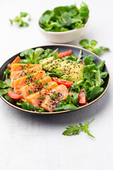 Salmon fish fillet with fresh salad, avocado top view.