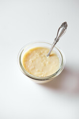 Dulce de leche, a typical Ecuadorian dessert served on a crystal jar with cinnamon on the side and a white background 