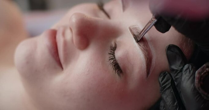 A beautician does henna eyebrow tinting for the young woman, cosmetological procedures and beautycare, 4k Prores 60p